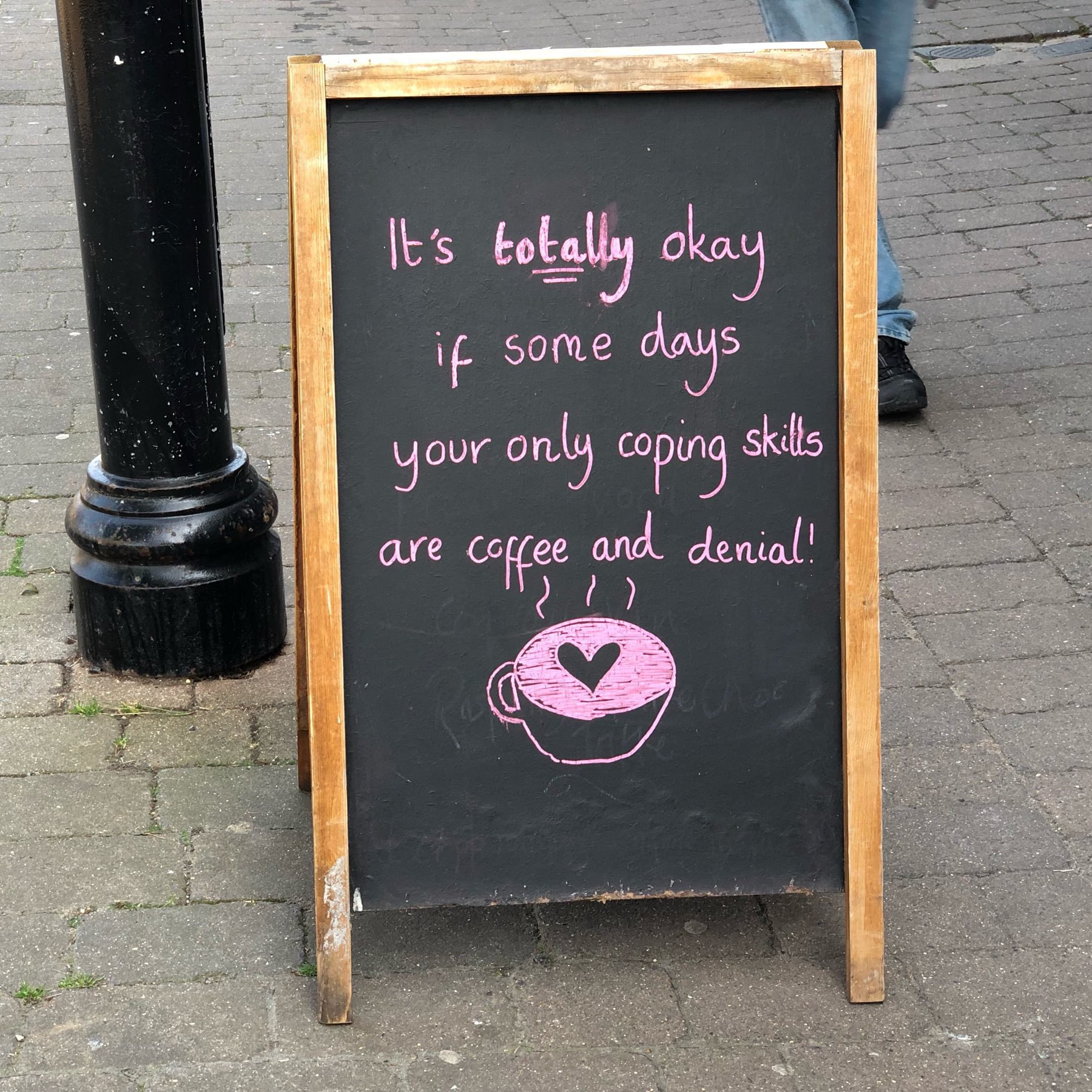 Sign sayin that coffee and denial are coping strategies some days, outside Ginger & Dobbs in Shoreham-by-Sea