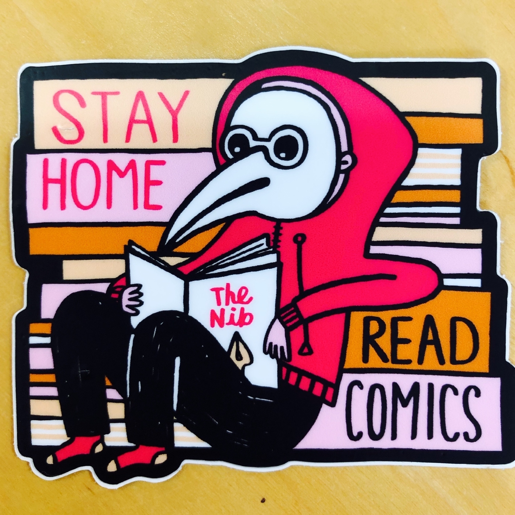 A sticker from The Nib saying "Stay Home, Read Comics"