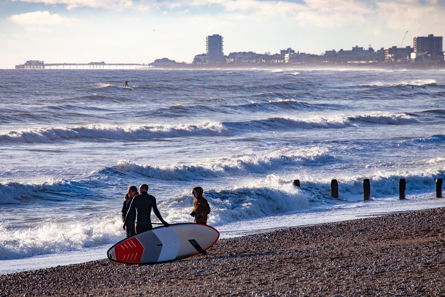 Surfers enjoying Shoreham Beach, with a view of Worthing Pier.