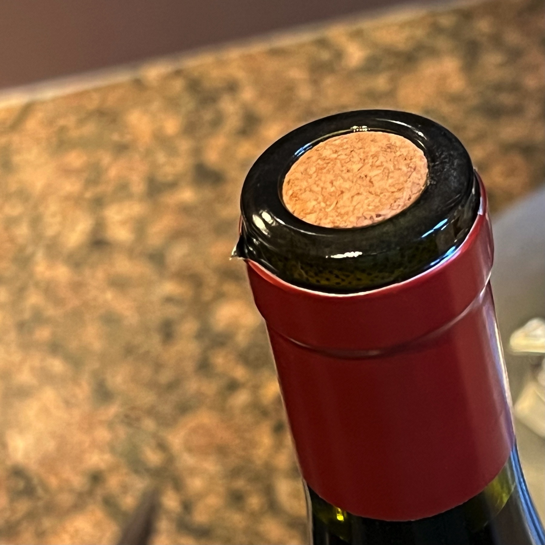 A bottle of red wine, about to have its cork removed. 