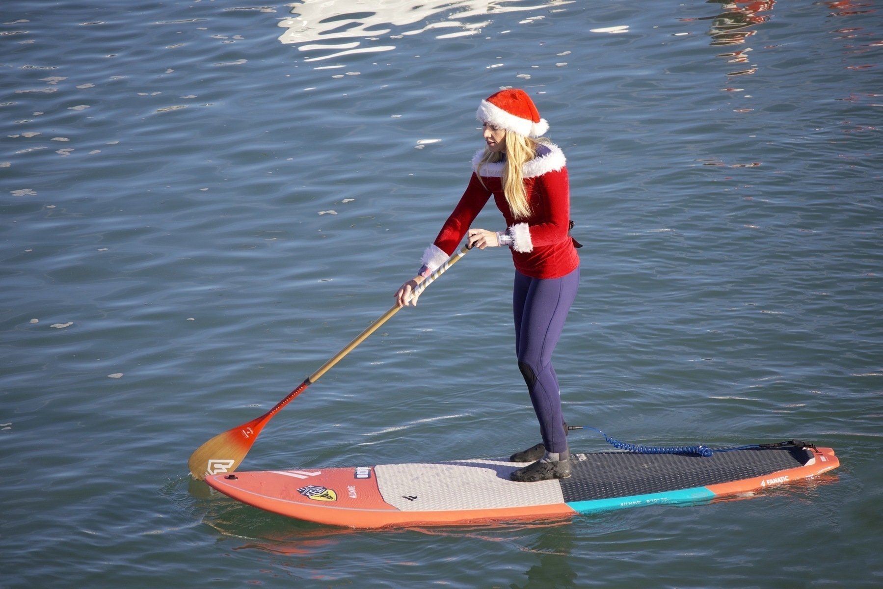 A stand-up paddleboarder in a Santa dress 