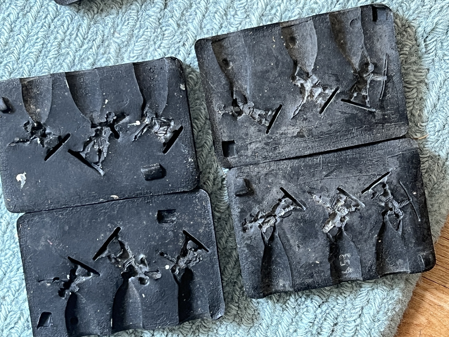 Two black molds with intricate patterns are placed on a textured fabric surface.