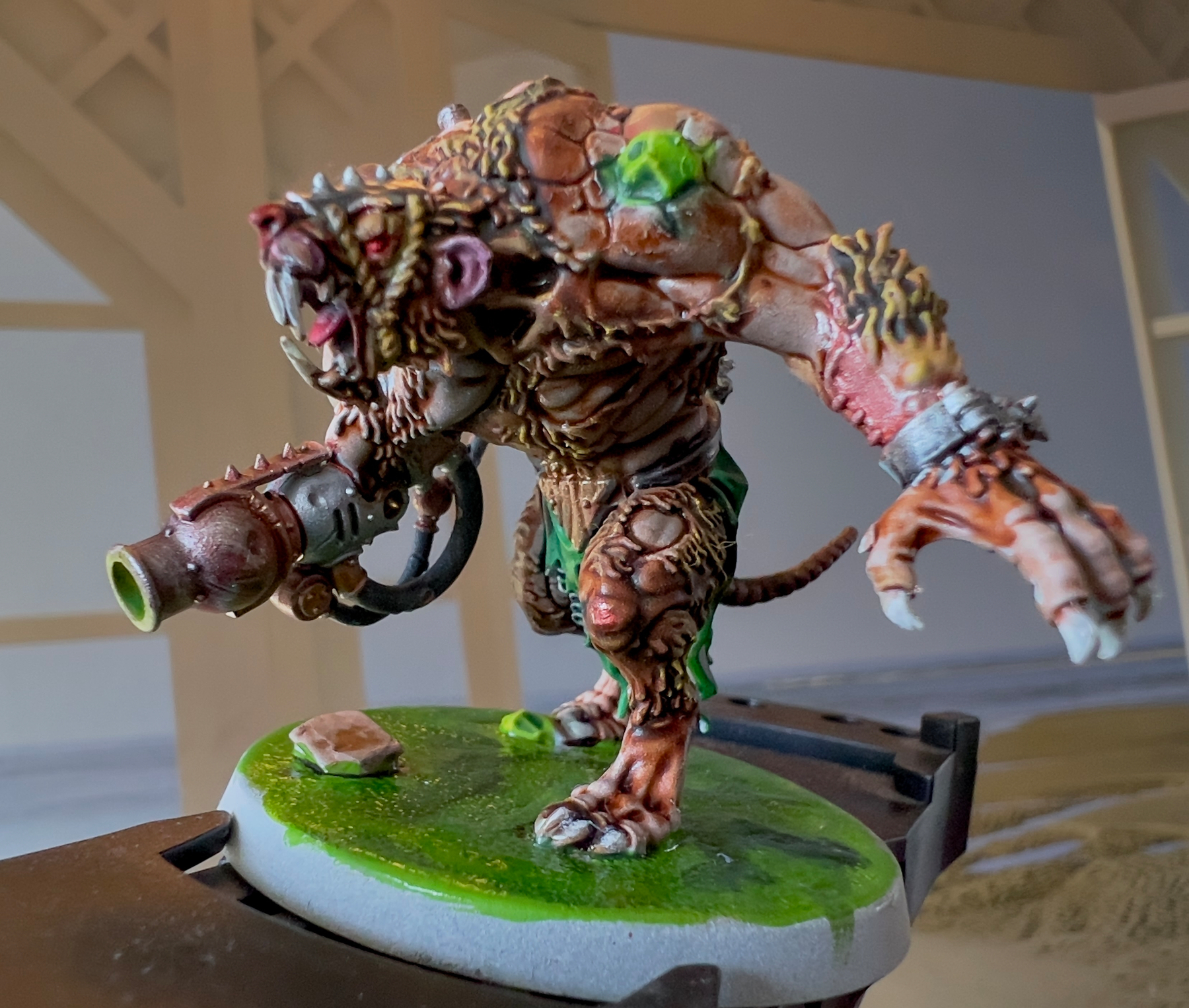 A detailed miniature figure of a fearsome, armored rat-like creature wielding a futuristic weapon stands on a painted base.