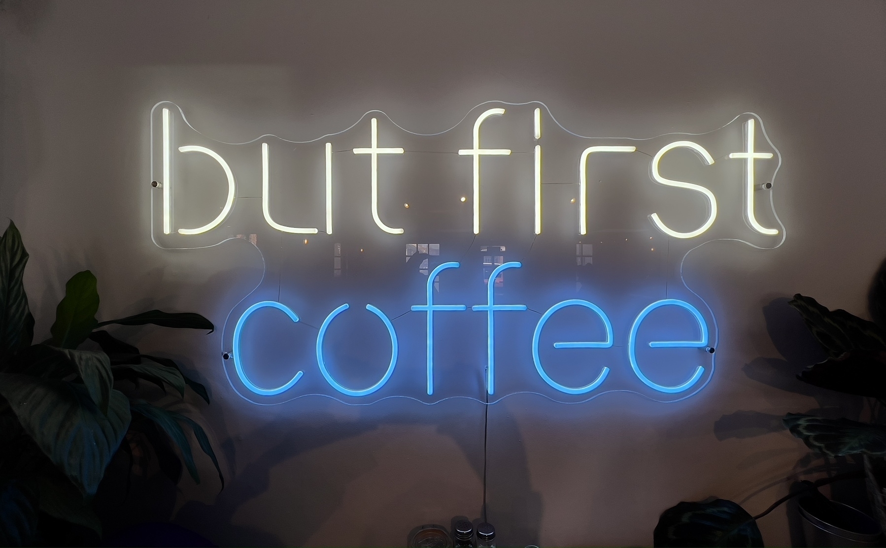 A neon sign reads "but first coffee," illuminated in white and blue. It’s in Clubhouse Coffee, Shoreham by Sea.