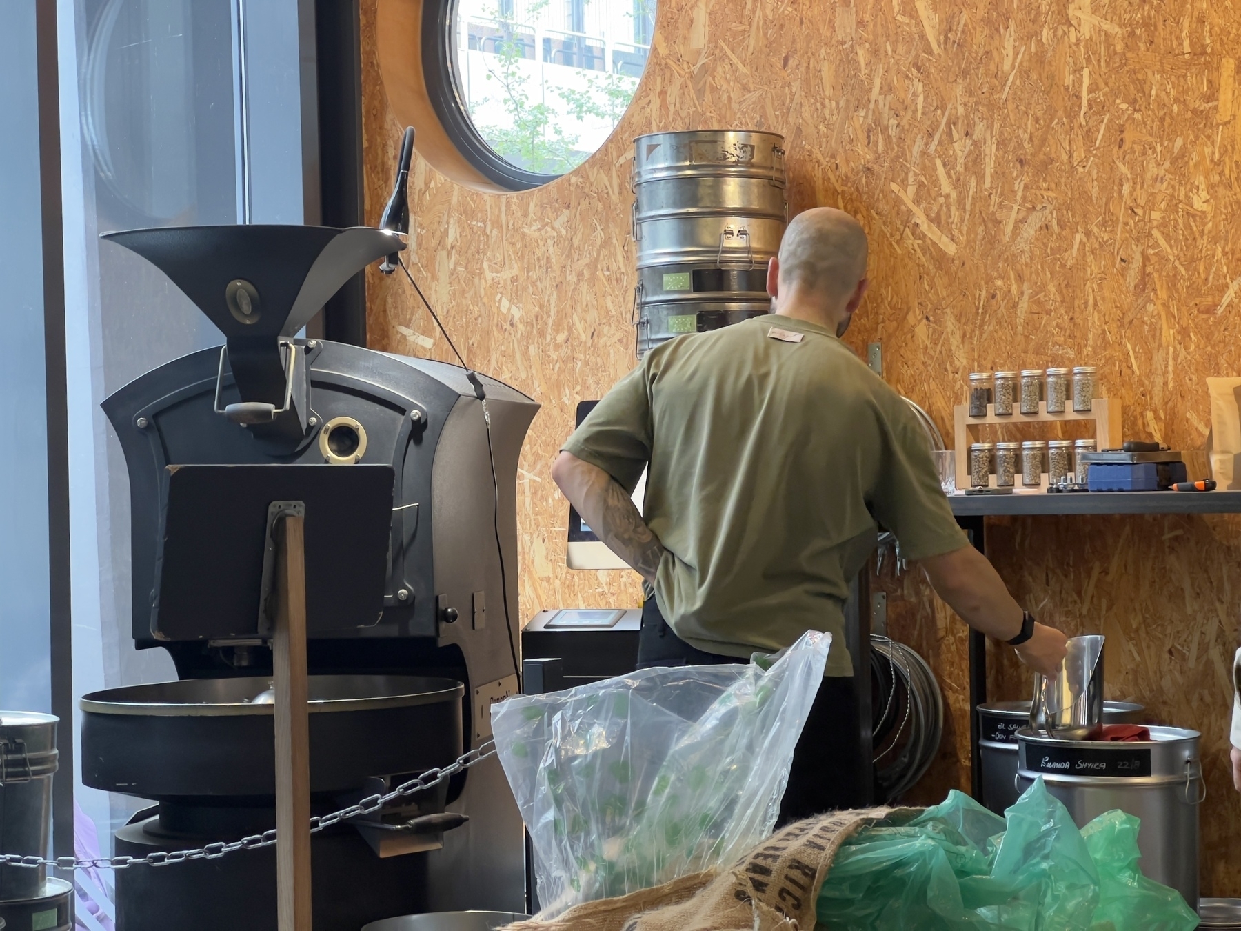 A man is working with coffee roasting equipment in an industrial-style setting.