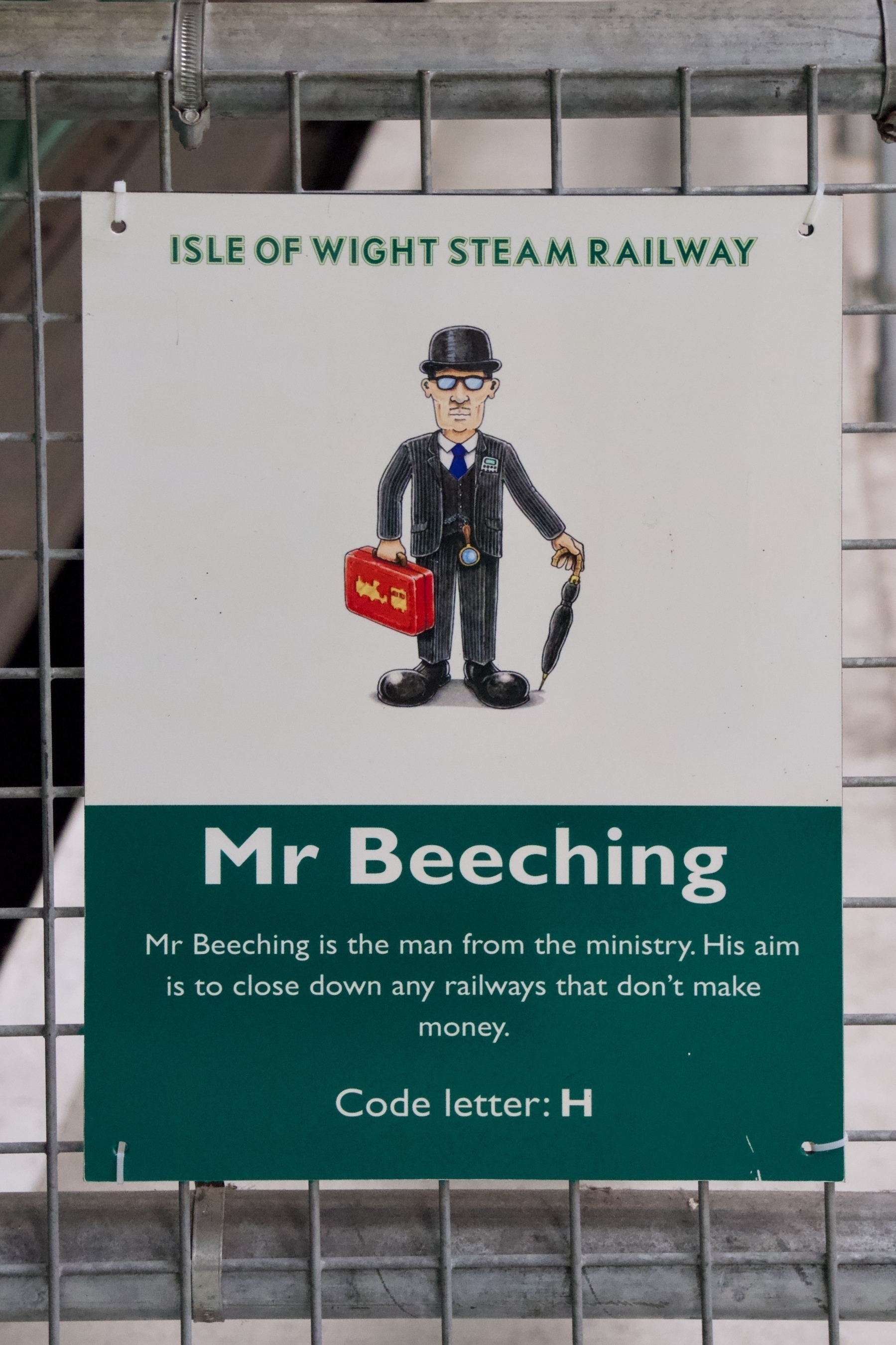 A cartoon character representing Mr. Beeching is depicted holding a red briefcase and an umbrella, with a note about his mission to close non-profitable railways at the Isle of Wight Steam Railway.
