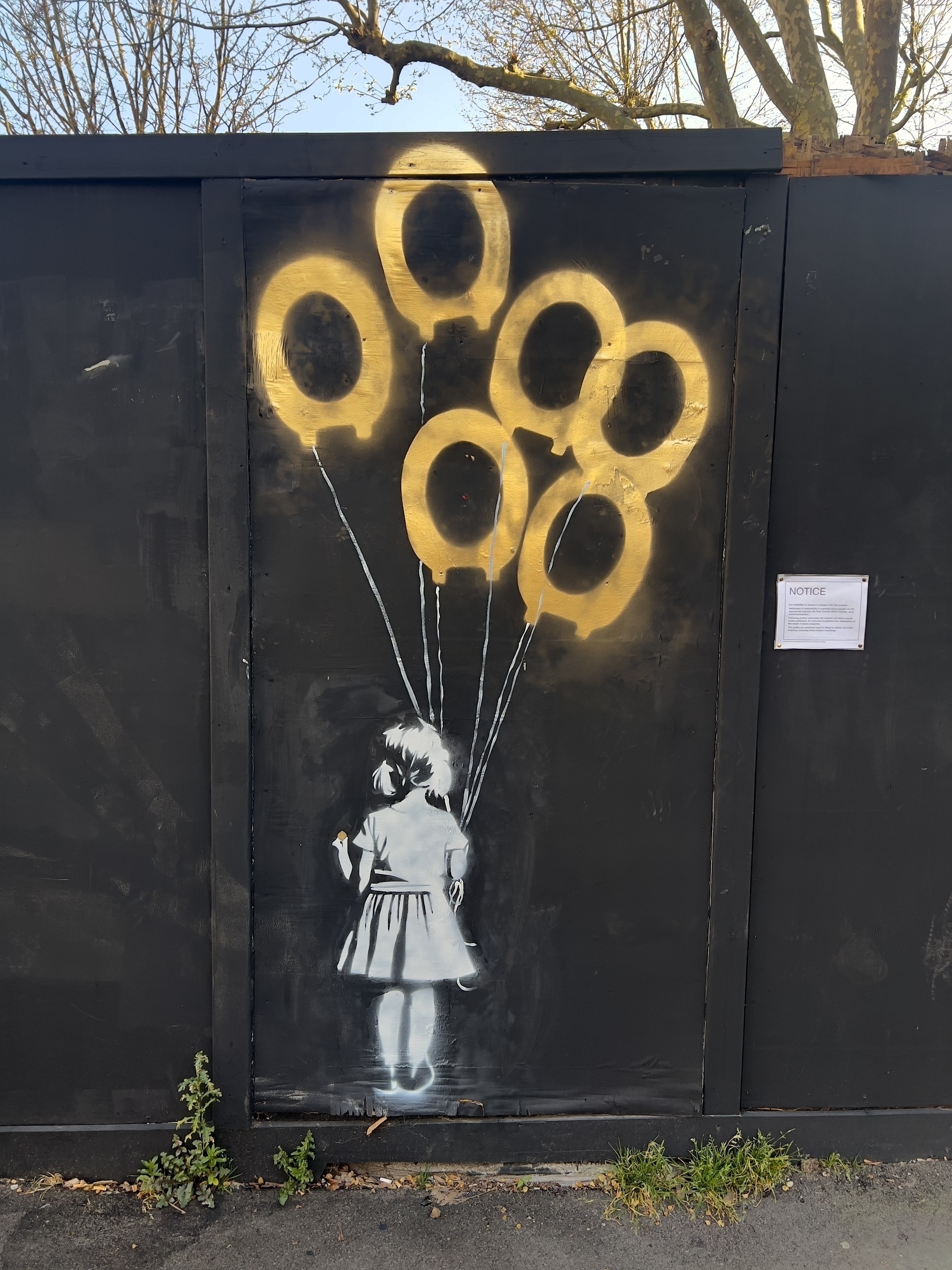 A stencil artwork depicts a child holding strings attached to golden, balloon-shaped outlines on a dark background.