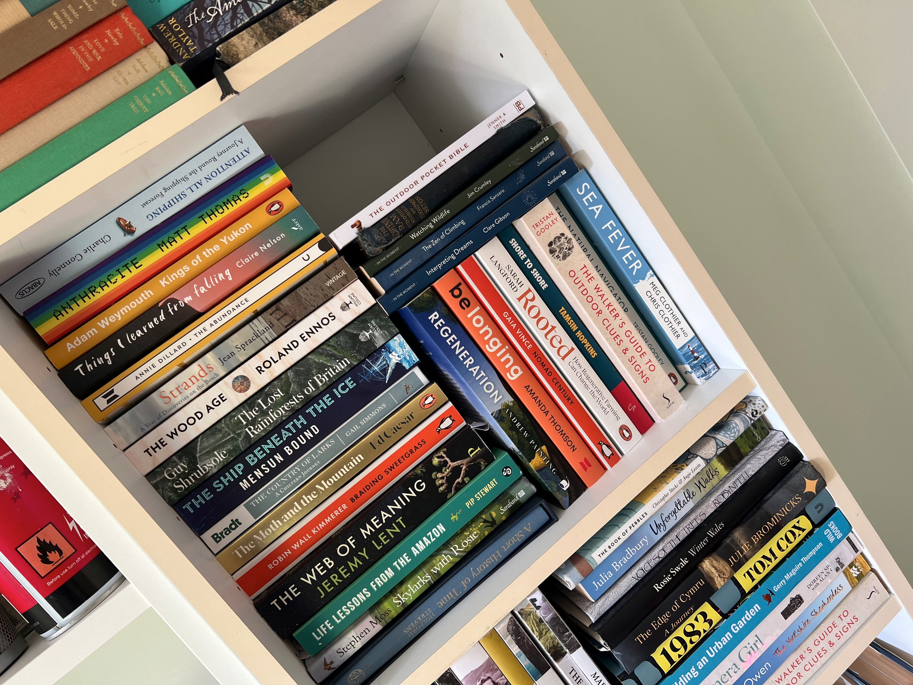 A bookshelf filled with a variety of books arranged both horizontally and vertically, covering topics from history and nature to personal growth and literature.