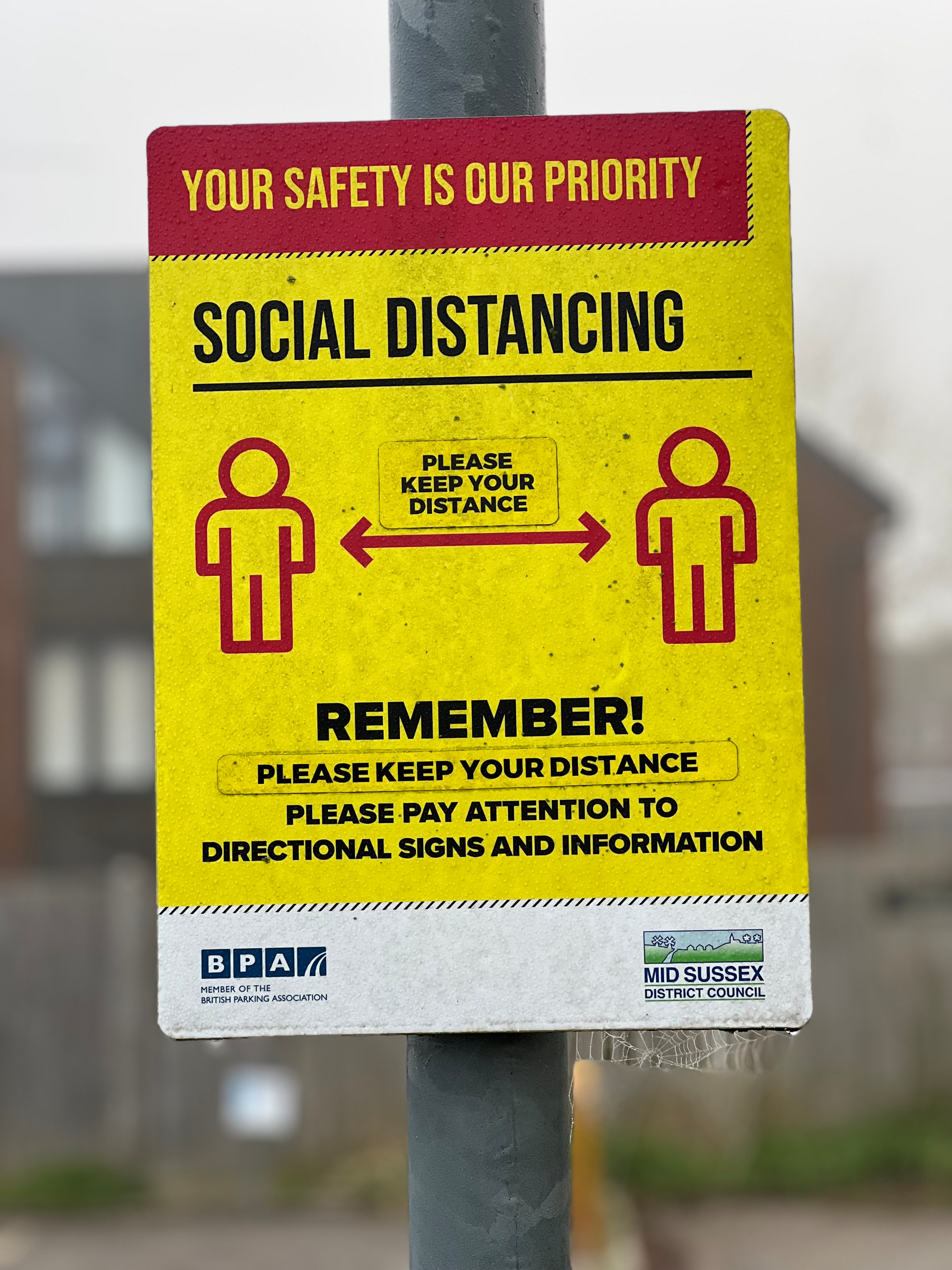 A social distancing sign emphasizes maintaining distance for safety, with instructions to stay informed through directional signs.